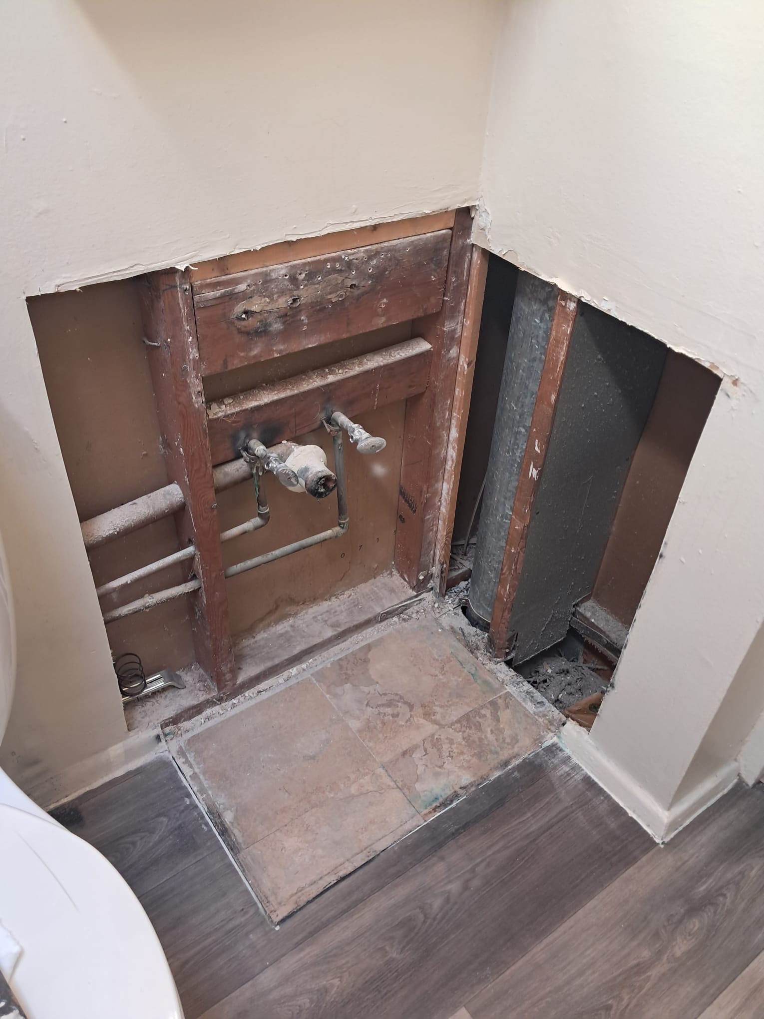 Bathroom wall open for vanity plumbing repair before drywall patch and paint