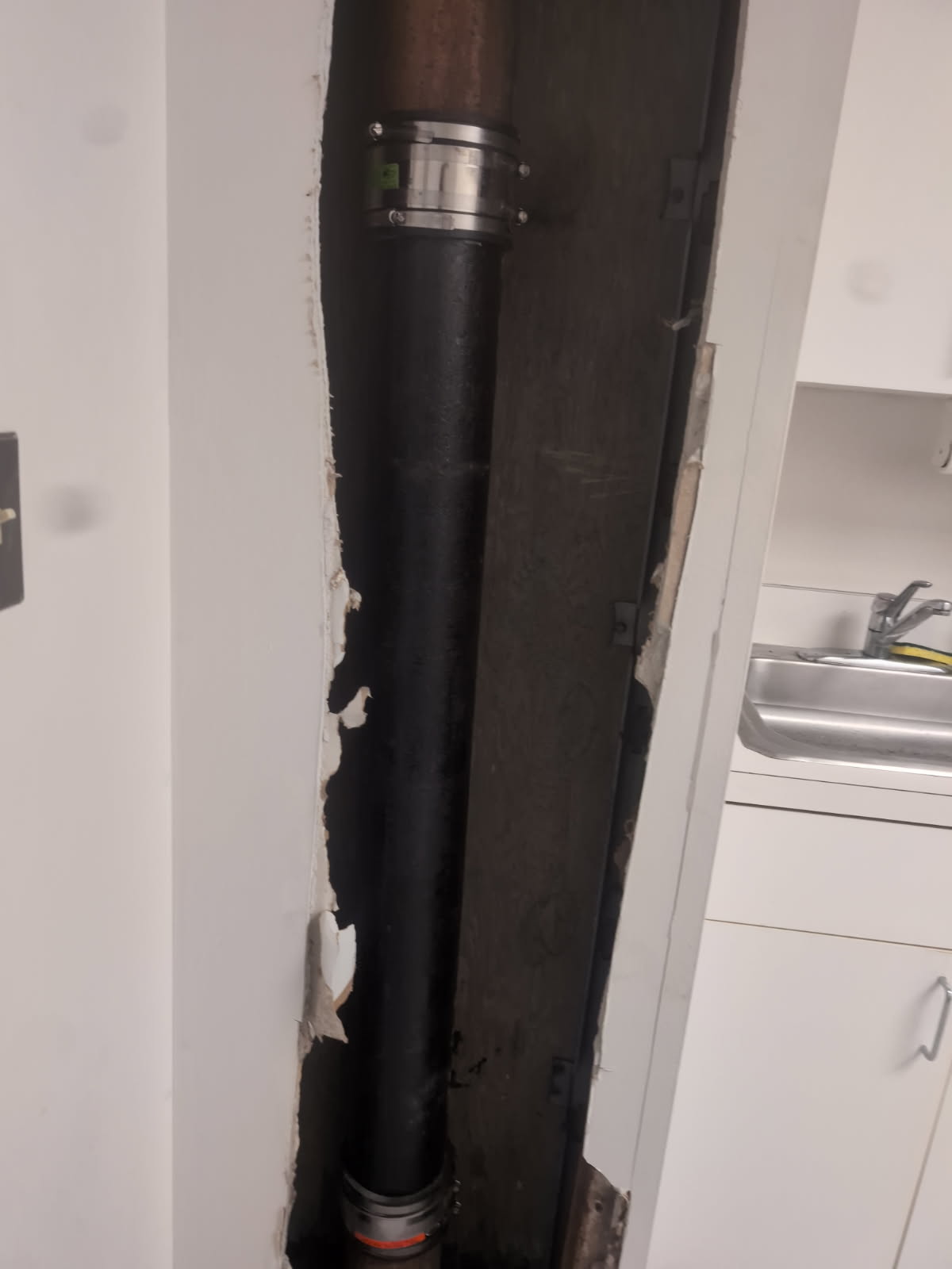 Open wall chase exposing pipes before drywall repair